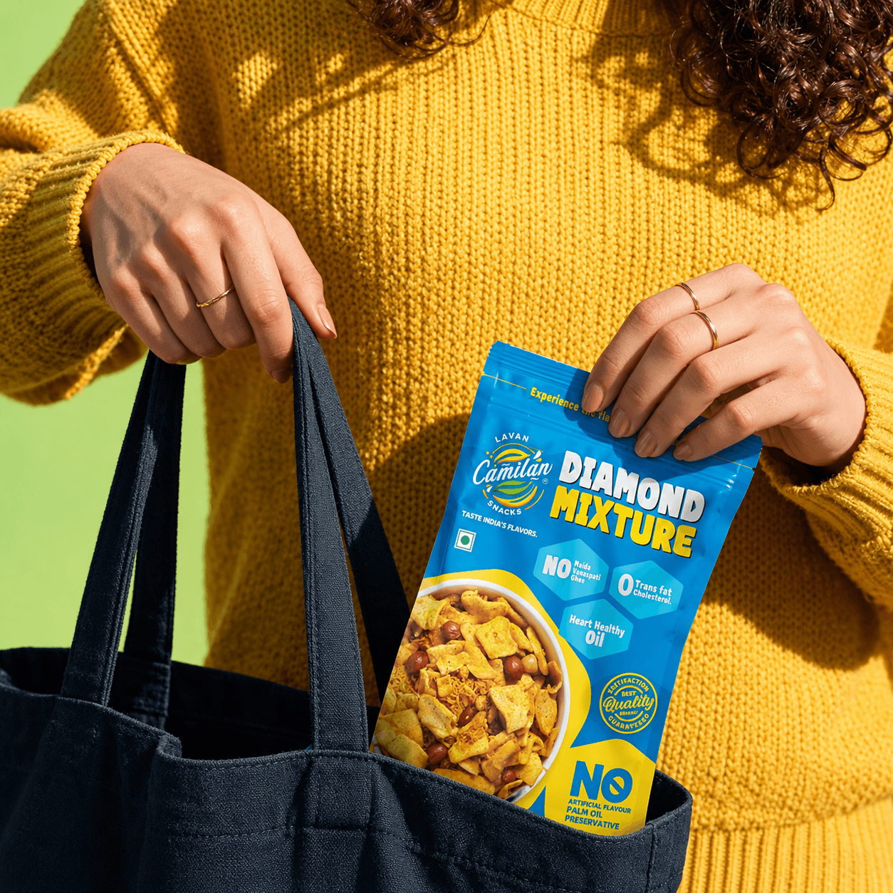 Woman in a yellow sweater placing a Diamond Mixture pouch into a black tote bag